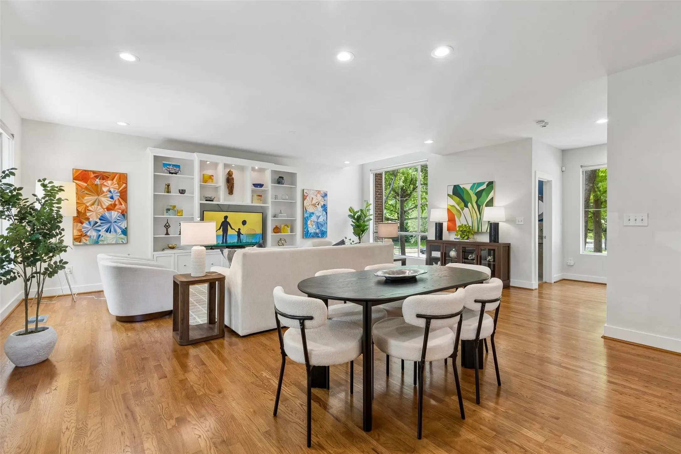 Open-concept living space featuring wood-finish flooring, recessed lighting, and large windows