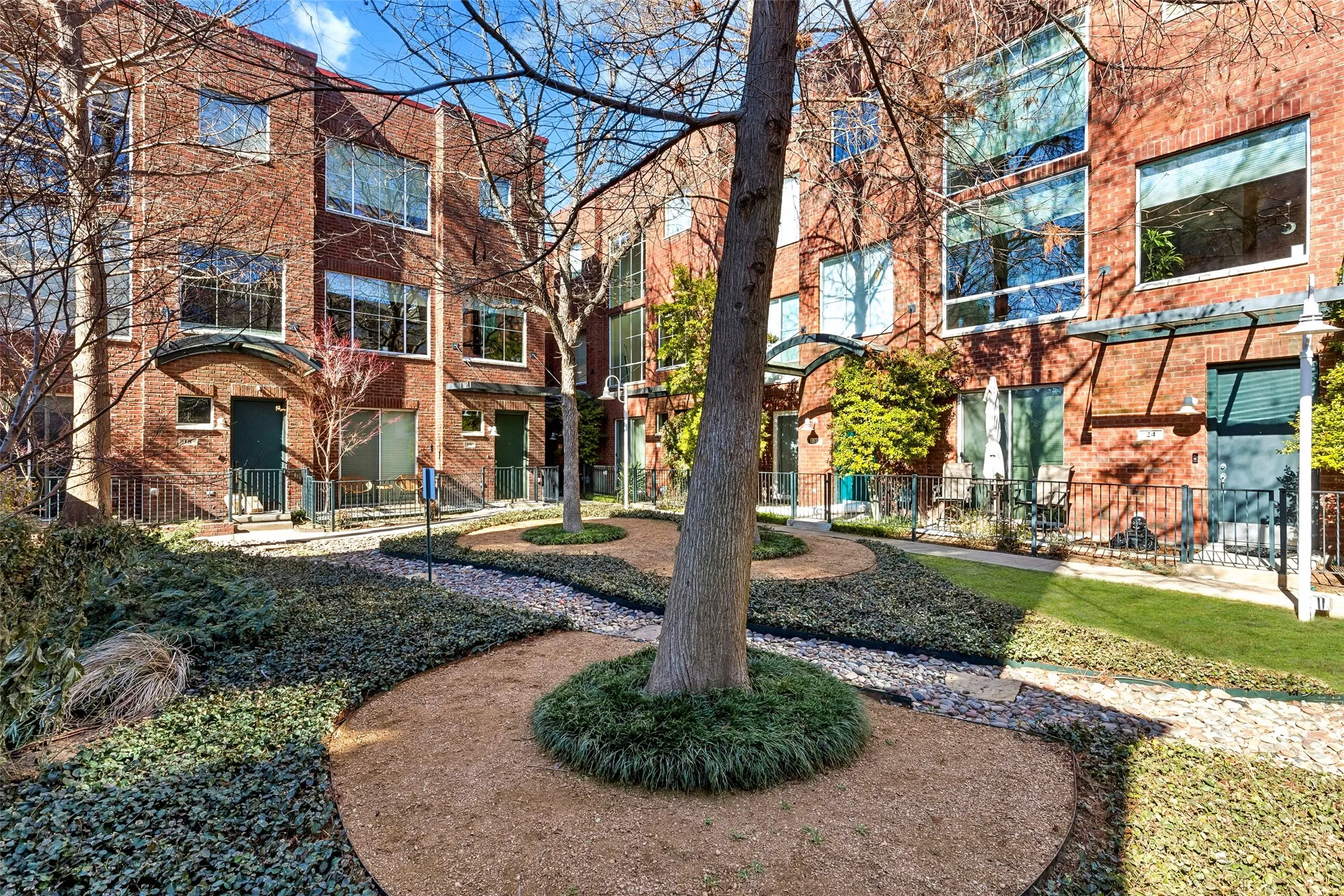 Brick facade townhome featuring multiple windows and a private patio space