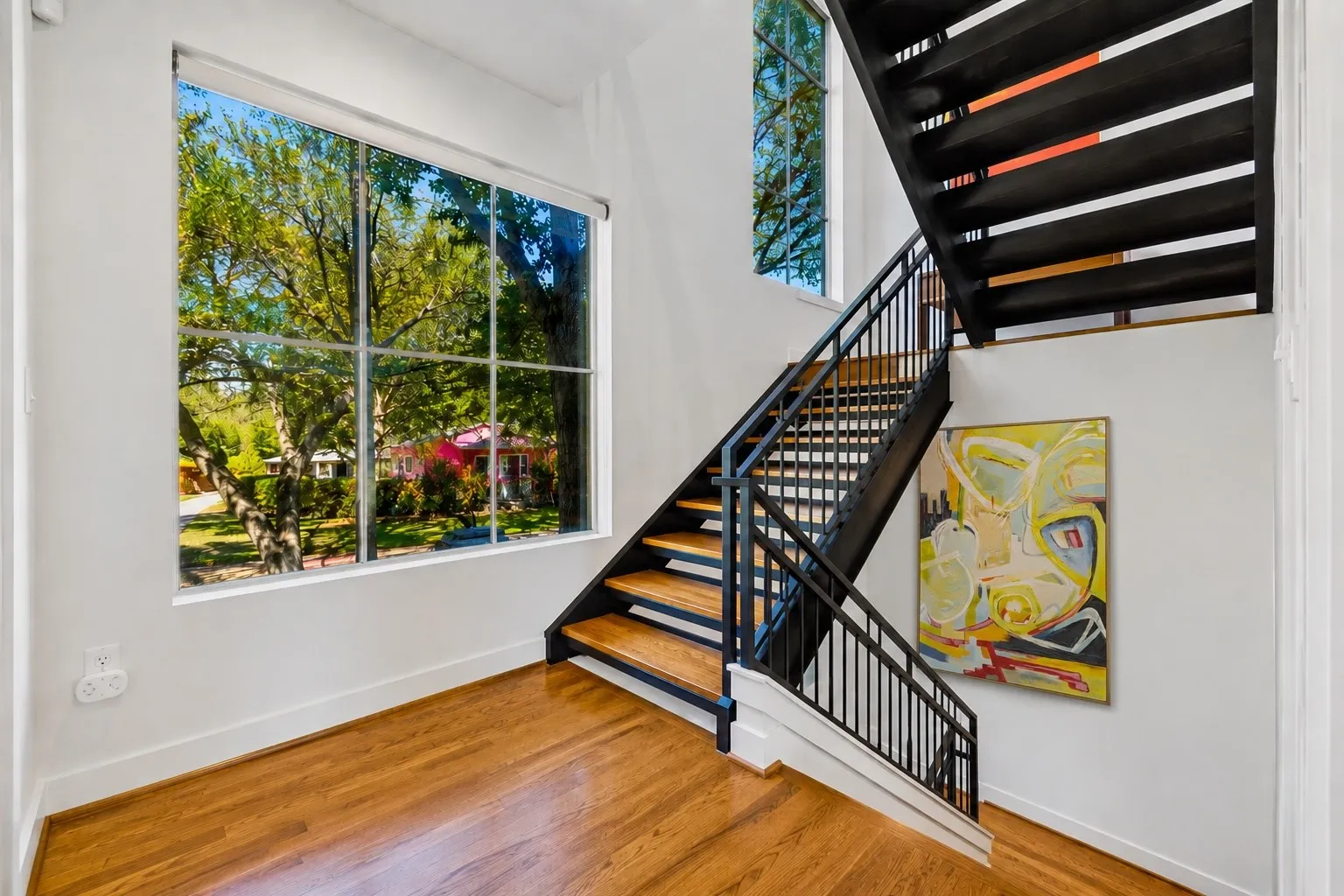 Hardwood flooring throughout, featuring a contemporary staircase with black metal railings and natural wood treads