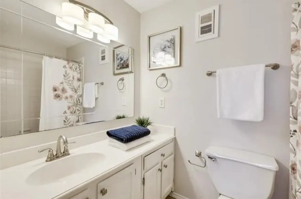 Bathroom featuring a vanity with a drop-in sink, white cabinetry, and a full-width mirror