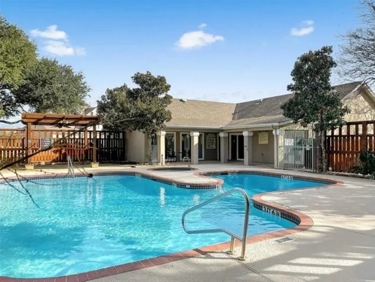 Resort-style swimming pool featuring an irregular shape, concrete decking, and a red brick coping