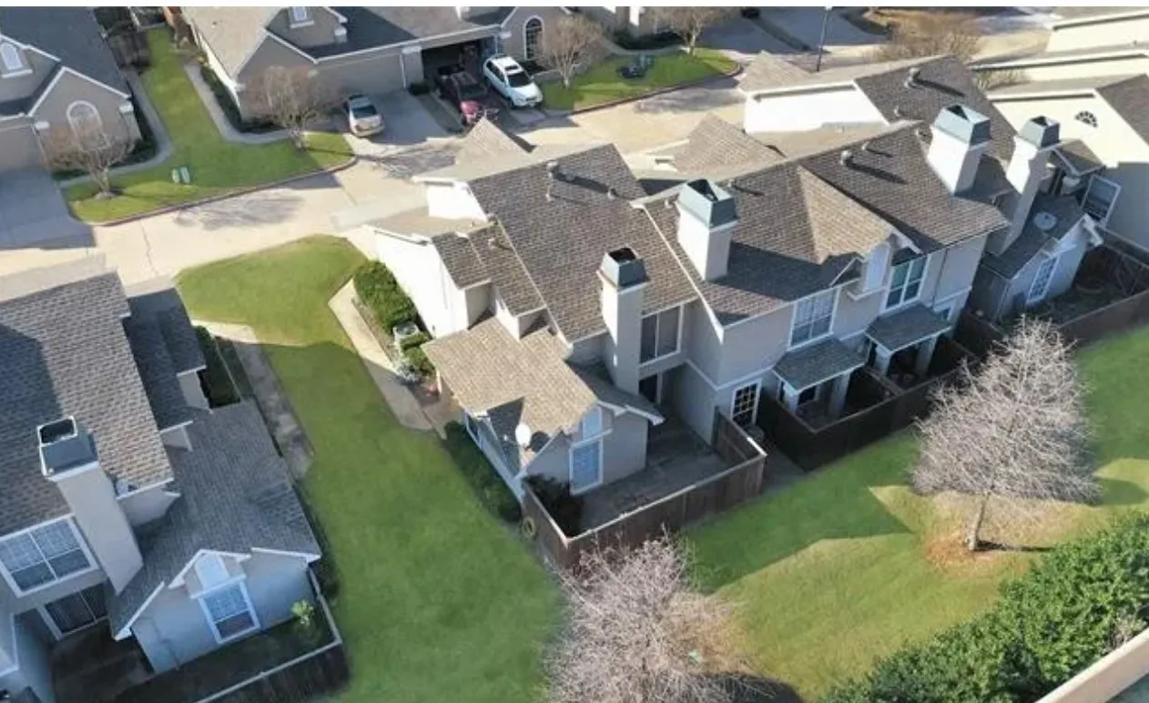 Townhome exterior featuring multiple chimneys, a private fenced patio, and varied rooflines