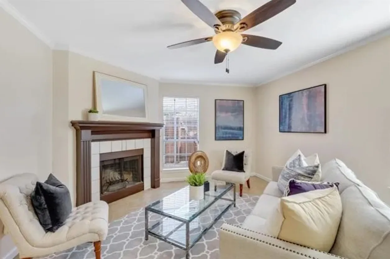 Living area featuring a fireplace with a wood mantle and tile surround, ceiling fan with integrated lighting, and crown molding