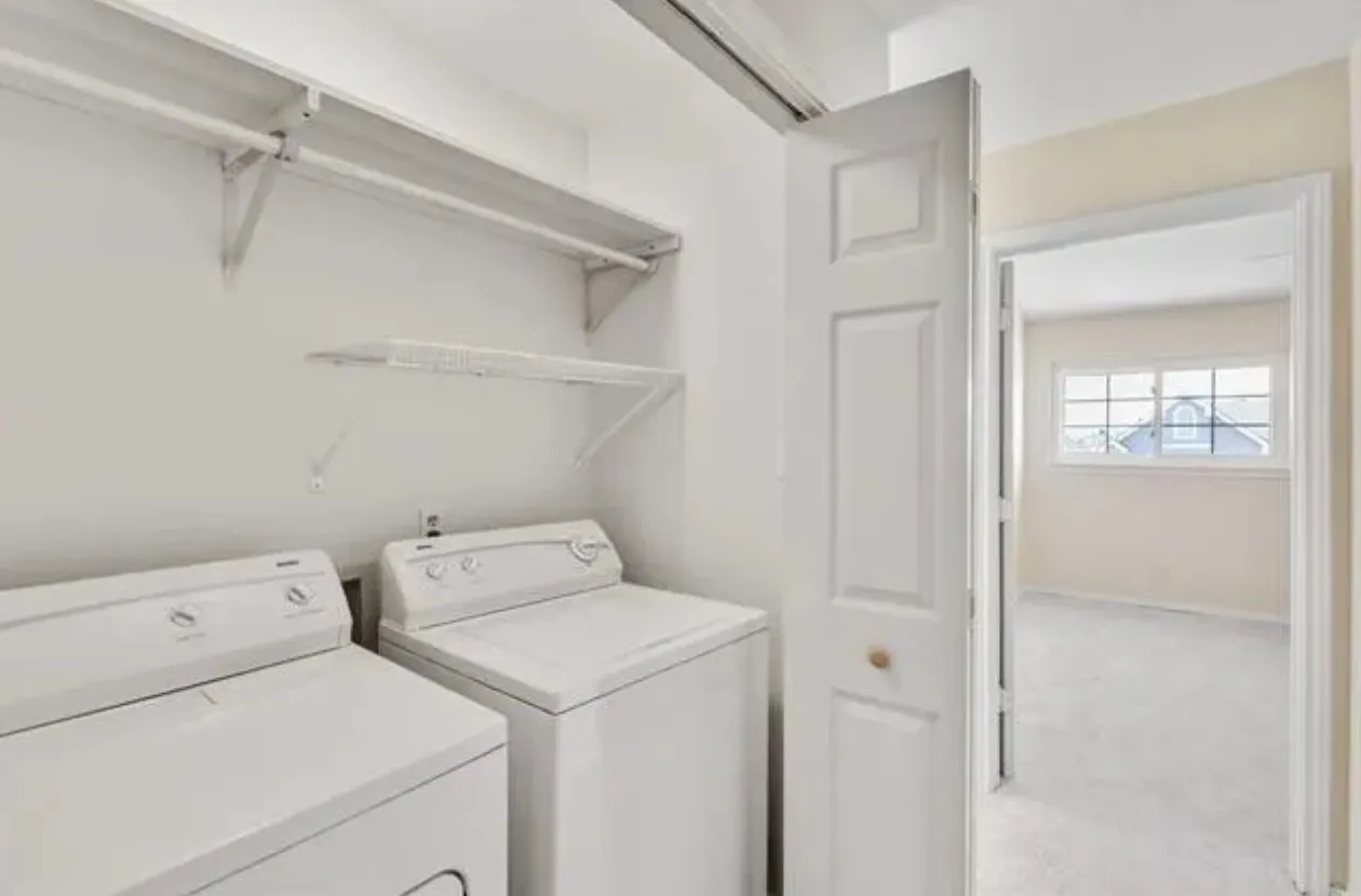 Dedicated laundry area featuring a full-sized washer and dryer, white shelving, and a hanging rod