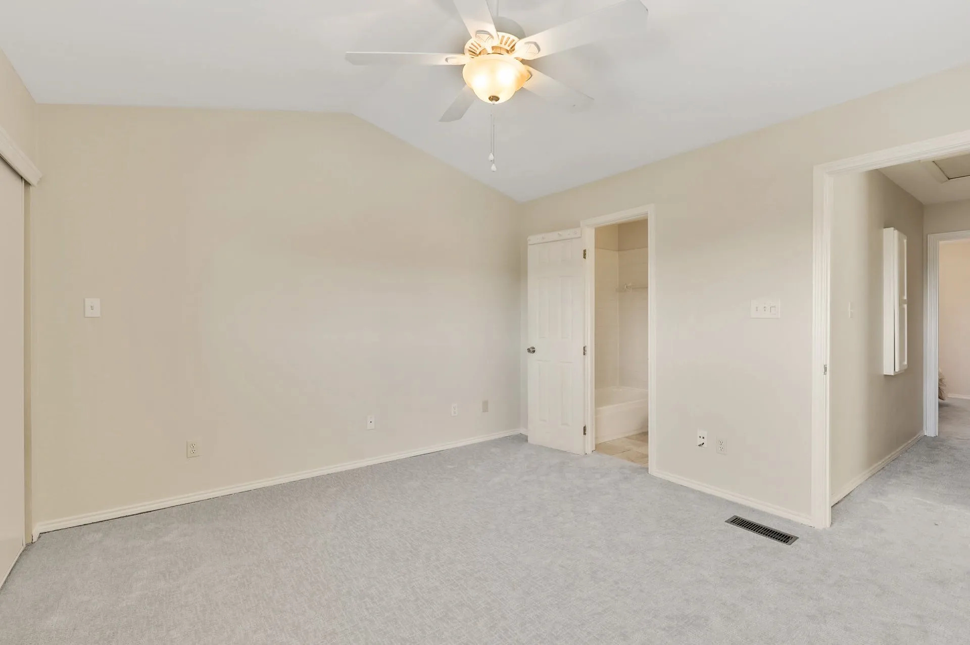 Carpeted interior room featuring a sloped ceiling and a ceiling fan with integrated lighting