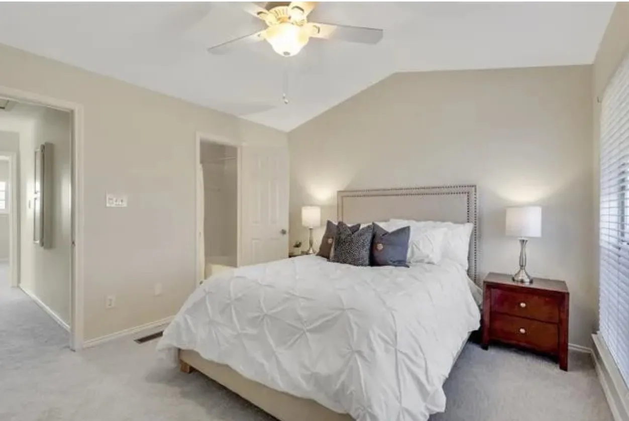 Vaulted ceiling with an illuminated ceiling fan, neutral wall paint, and plush carpet flooring