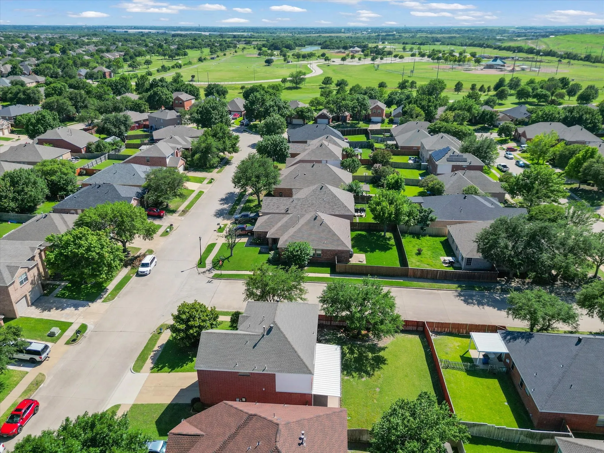 Residential neighborhood featuring mature trees, paved streets, and green spaces