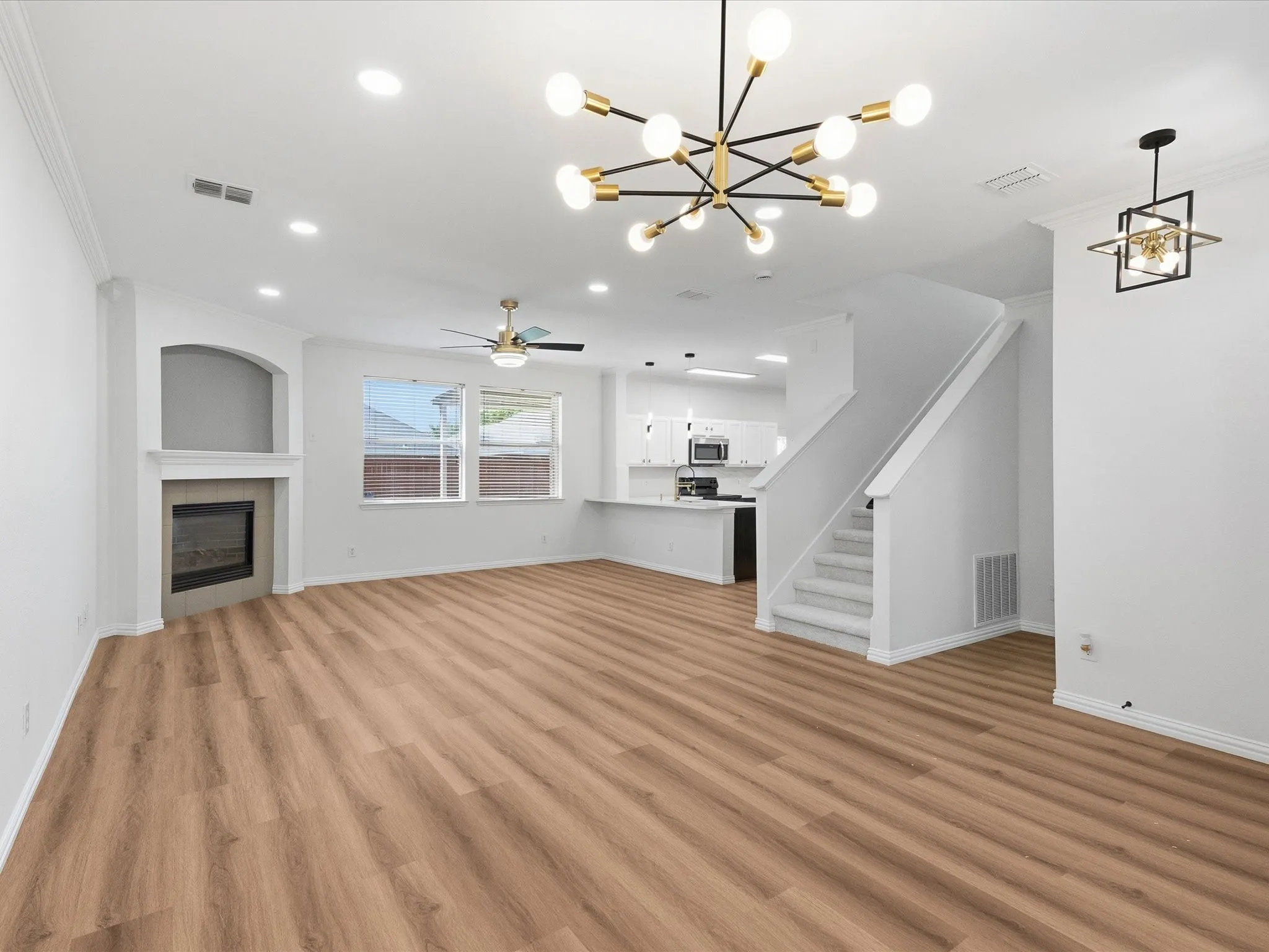 Spacious open-concept living area featuring wood-finish flooring, a fireplace with a mantel, and recessed lighting