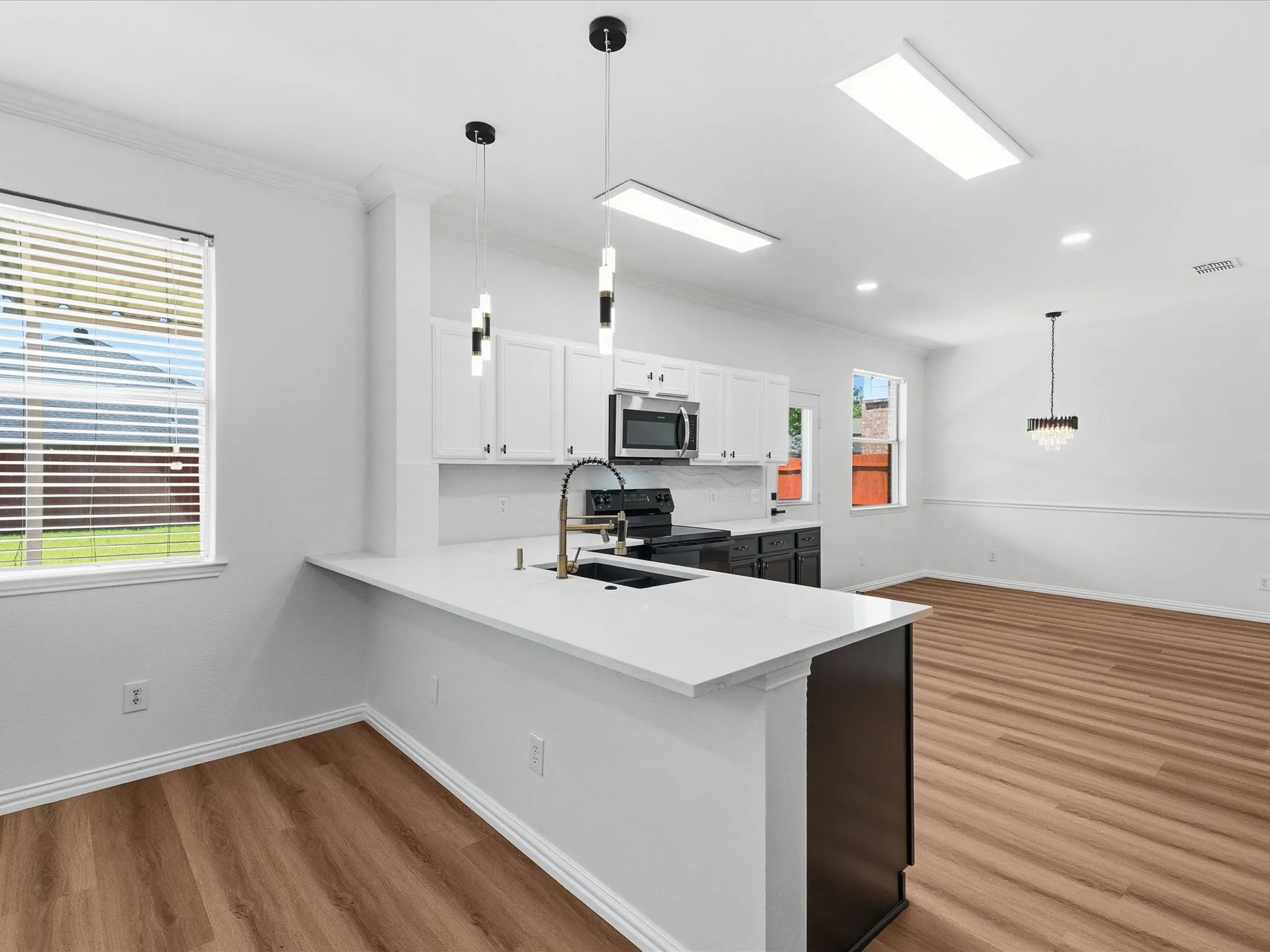 Modern kitchen featuring white shaker cabinetry, stainless steel appliances, a white solid surface countertop, and wood-finish flooring