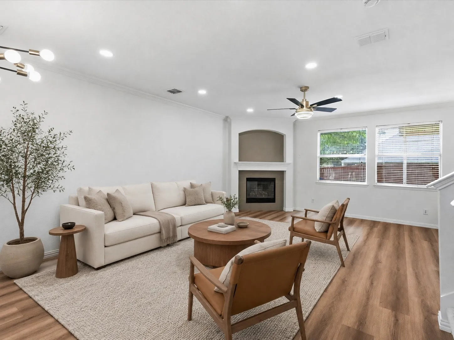 Recessed lighting illuminates this living space featuring wood-finish flooring, a built-in fireplace with mantel, and large windows