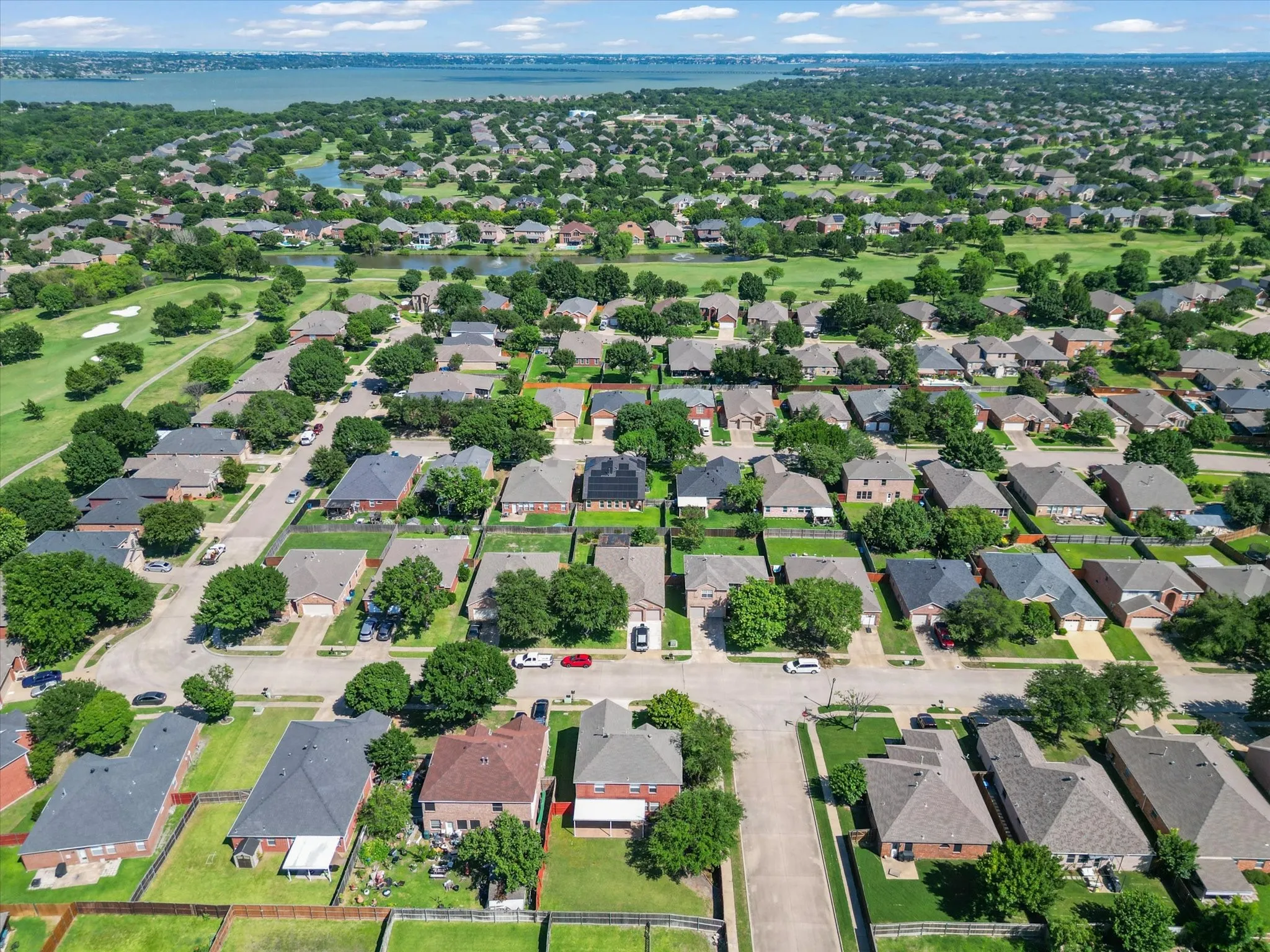 Residential neighborhood with a golf course, expansive lake, and mature trees