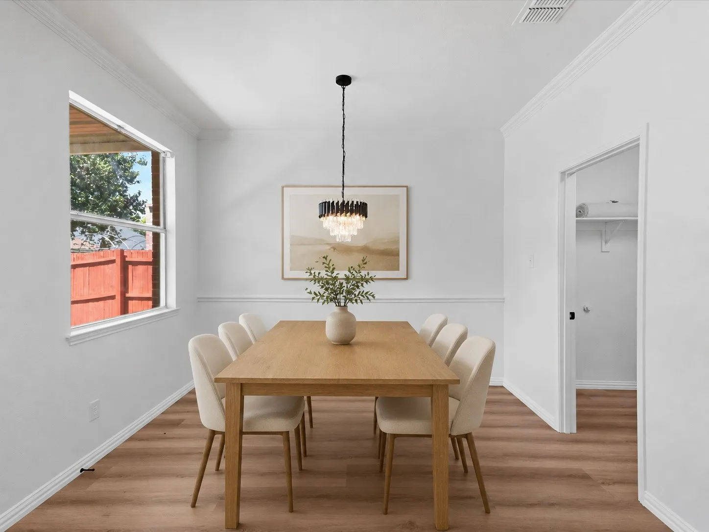 Dining area featuring wood-finish flooring, a window, crown molding, chair rail molding, and a built-in closet with shelving