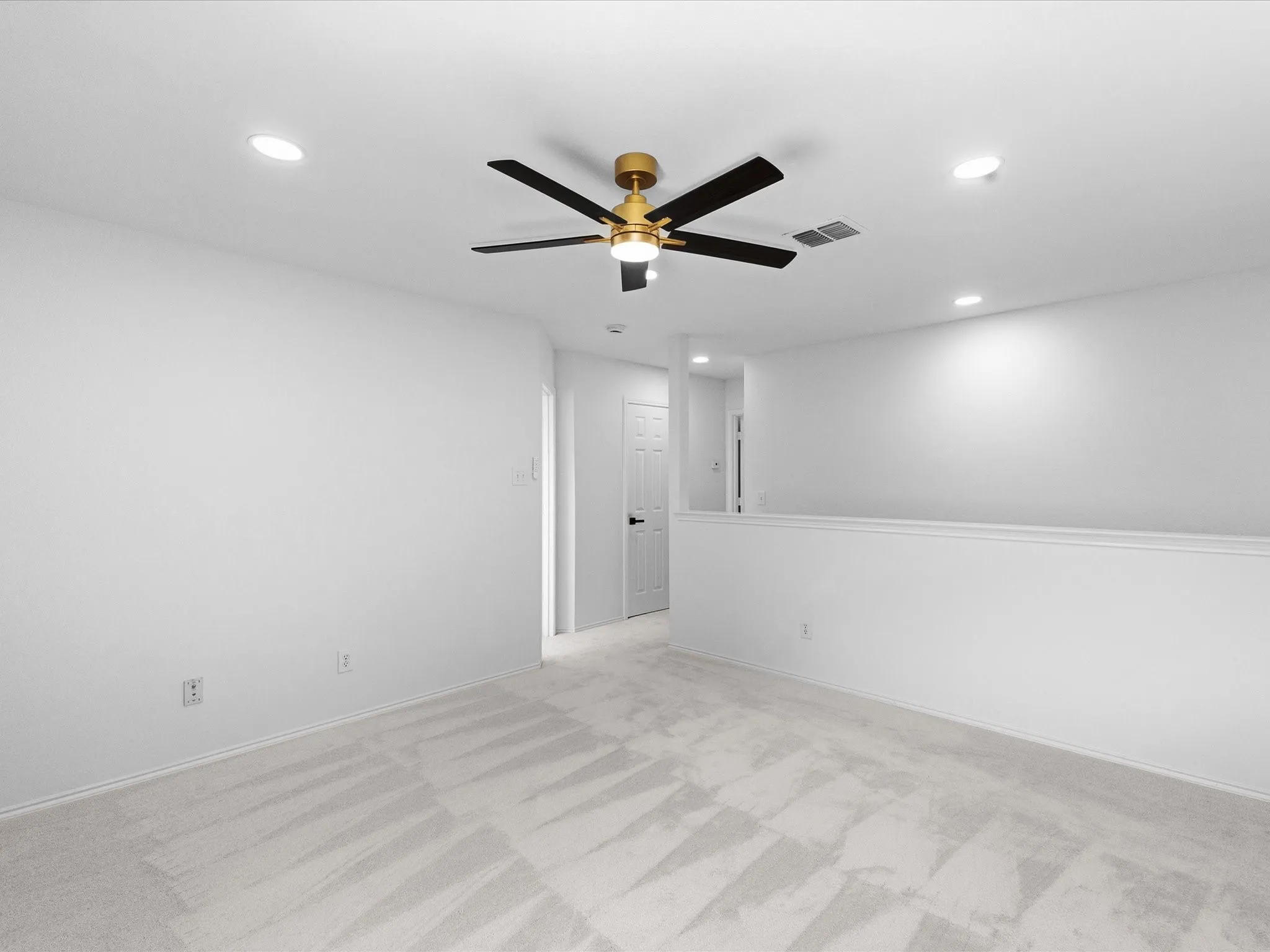 Carpeted open loft area featuring a gold and black ceiling fan, recessed lighting, and a partial wall overlooking the space below
