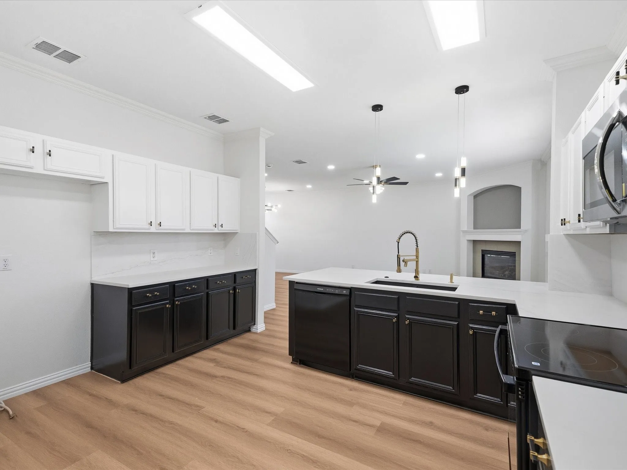 Kitchen featuring two-tone cabinetry, light countertops, wood-finish flooring, and a large island with an integrated sink and gooseneck faucet