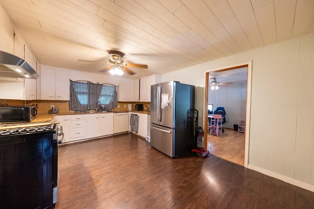 Kitchen featuring wood-finish flooring, white cabinetry, and wood-finish countertops
