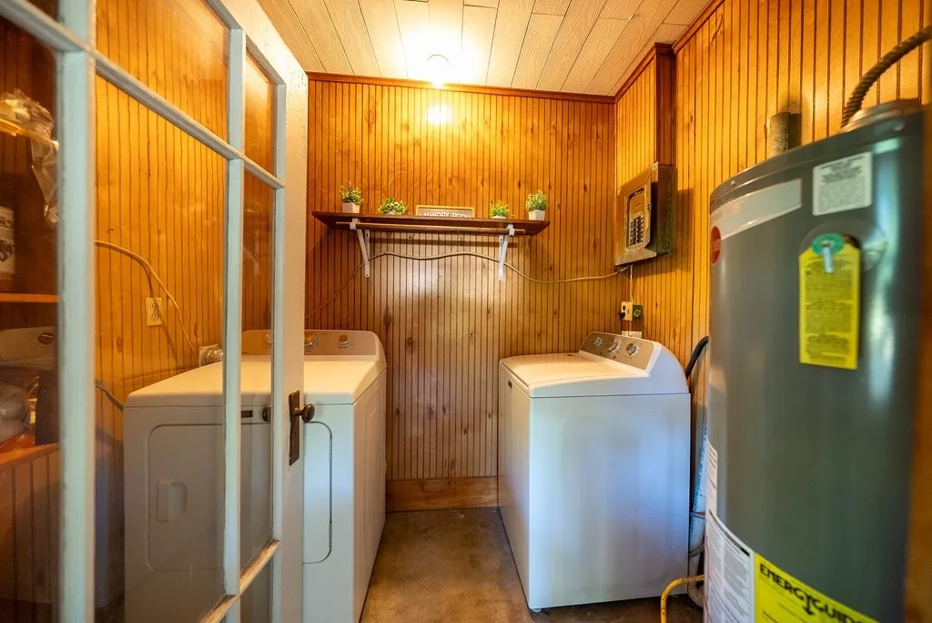 Utility room featuring wood-finish paneling, a built-in shelf, and a ceiling-mounted light fixture