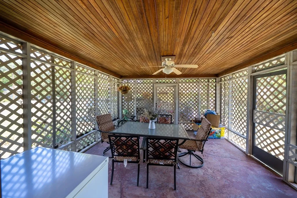 Screened porch featuring a wood-paneled ceiling with a ceiling fan, lattice walls, and a concrete floor