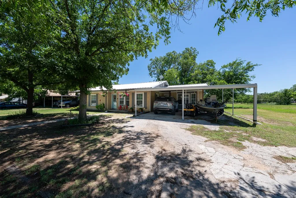 Single-story residence featuring a metal roof, extended carport, and light-colored siding