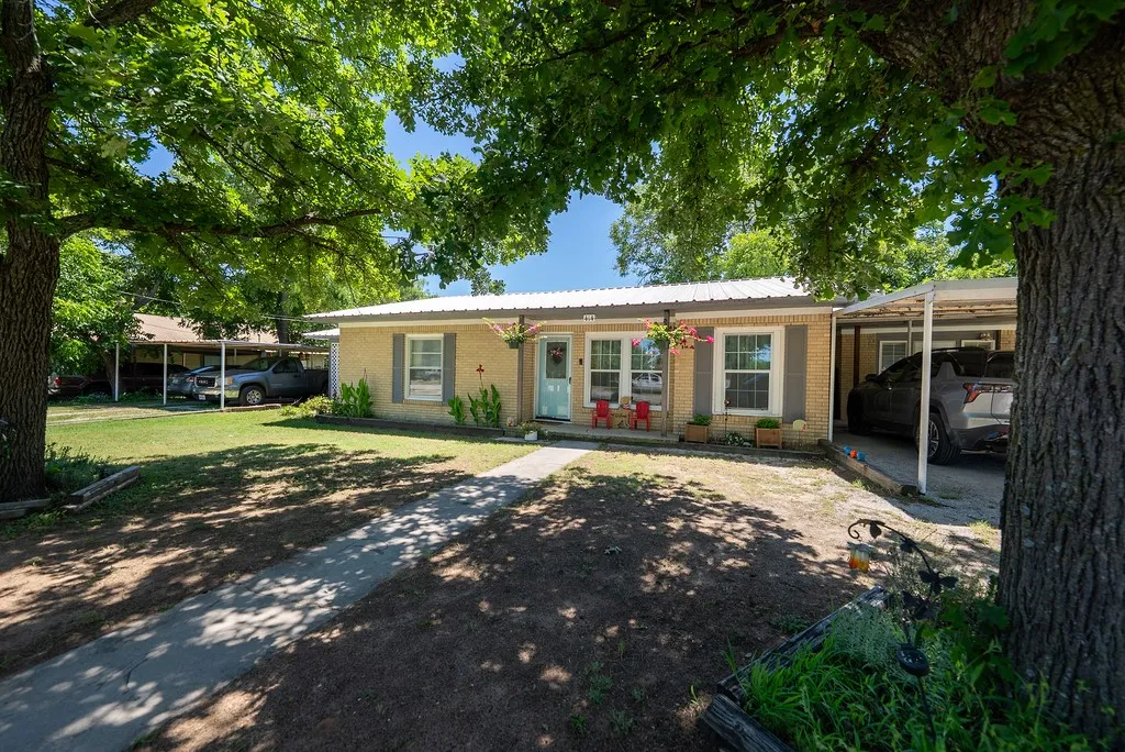 Ranch-style exterior with brick facade, a metal roof, and a covered carport