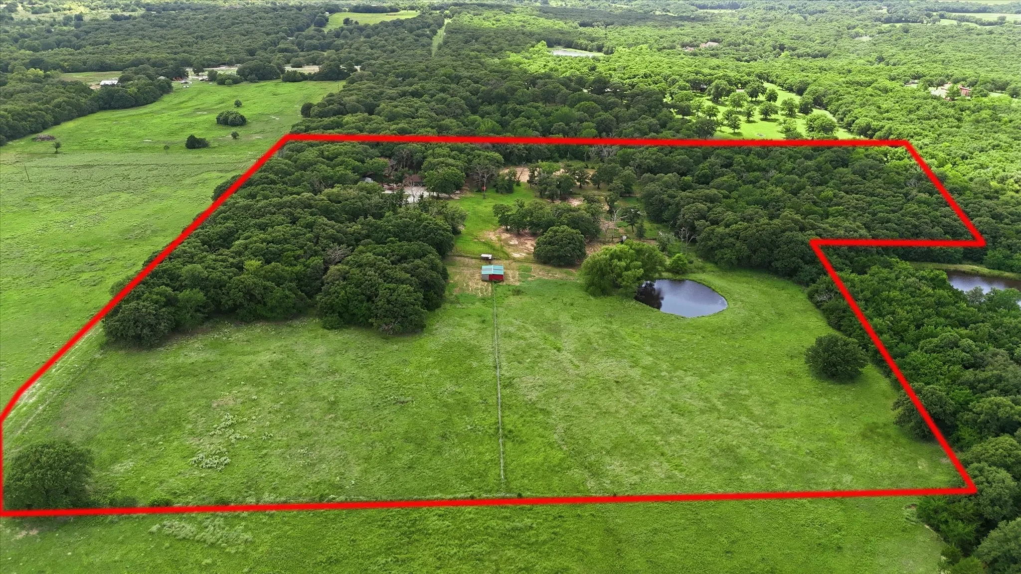 Expansive acreage featuring a mix of open grassy areas and mature tree coverage