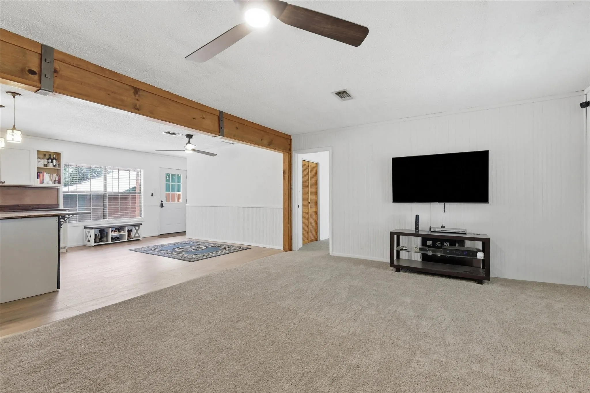 Spacious living area featuring light-toned carpet and a ceiling fan