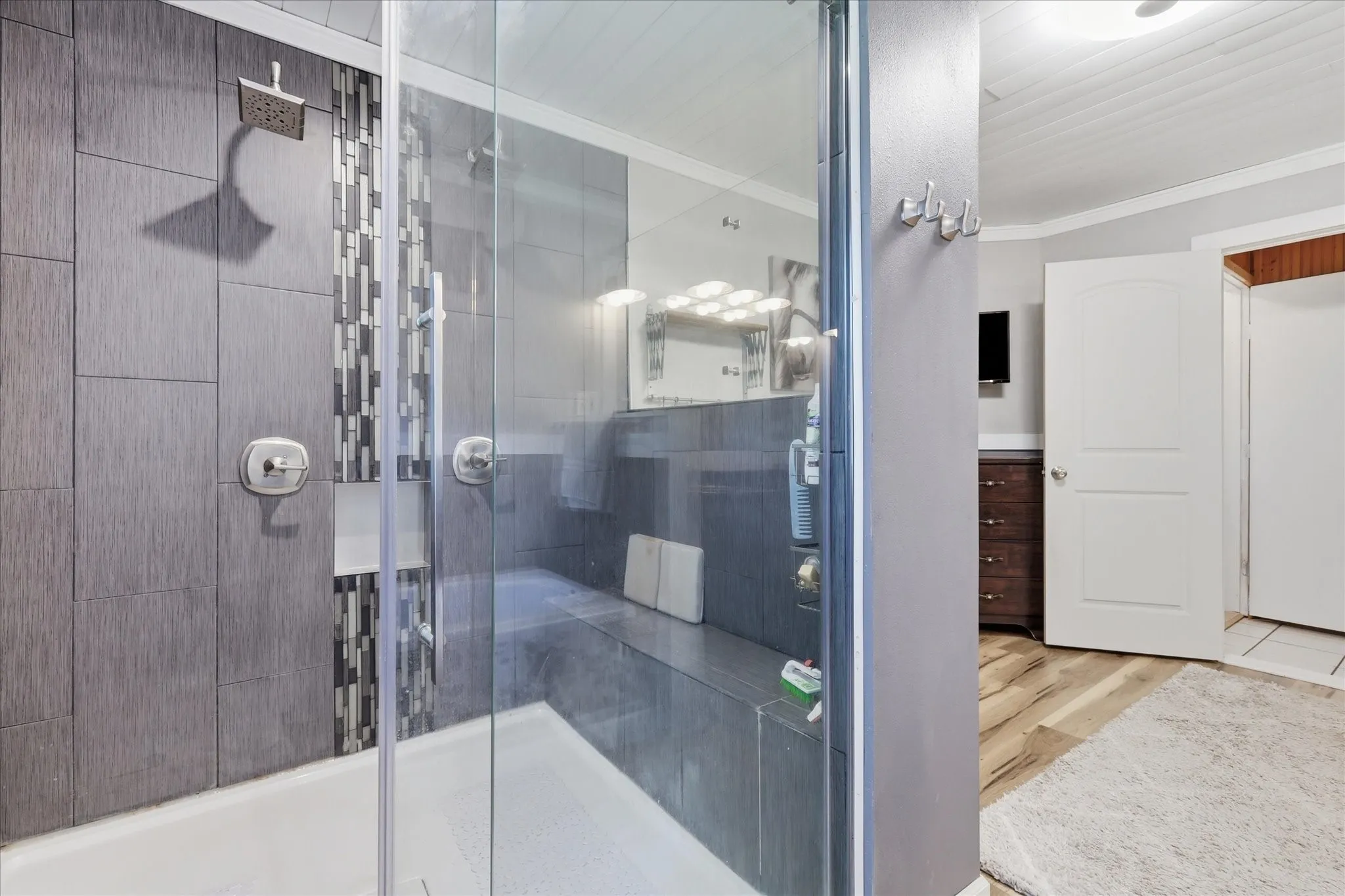 Walk-in shower with clear glass enclosure and built-in bench