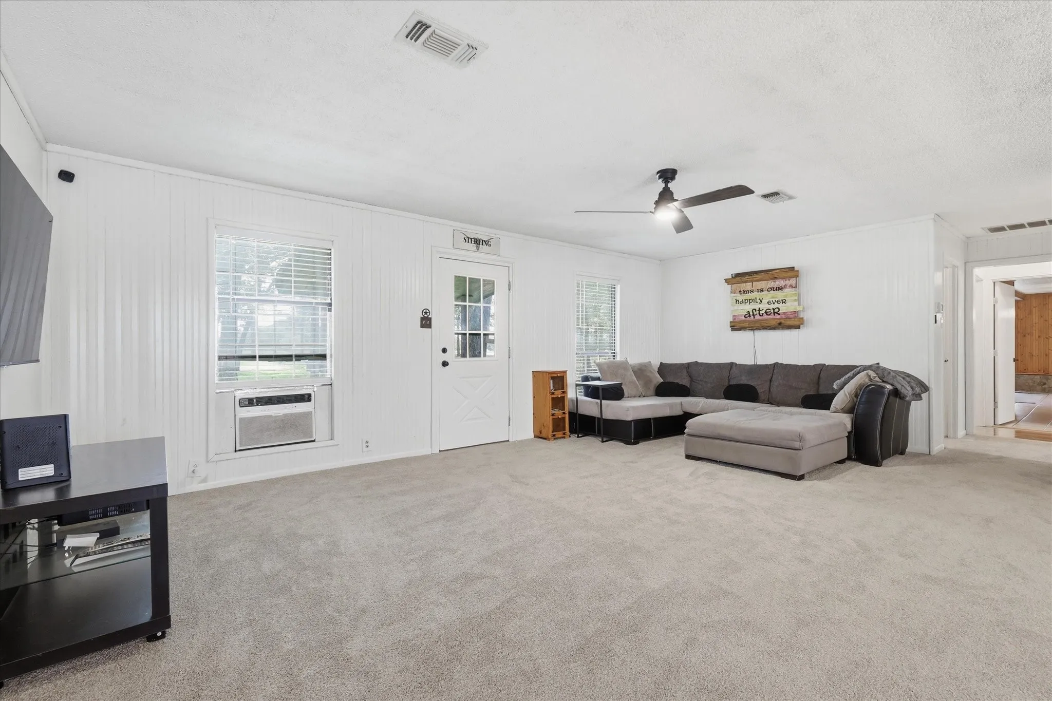 Spacious carpeted room featuring white vertical paneling on walls