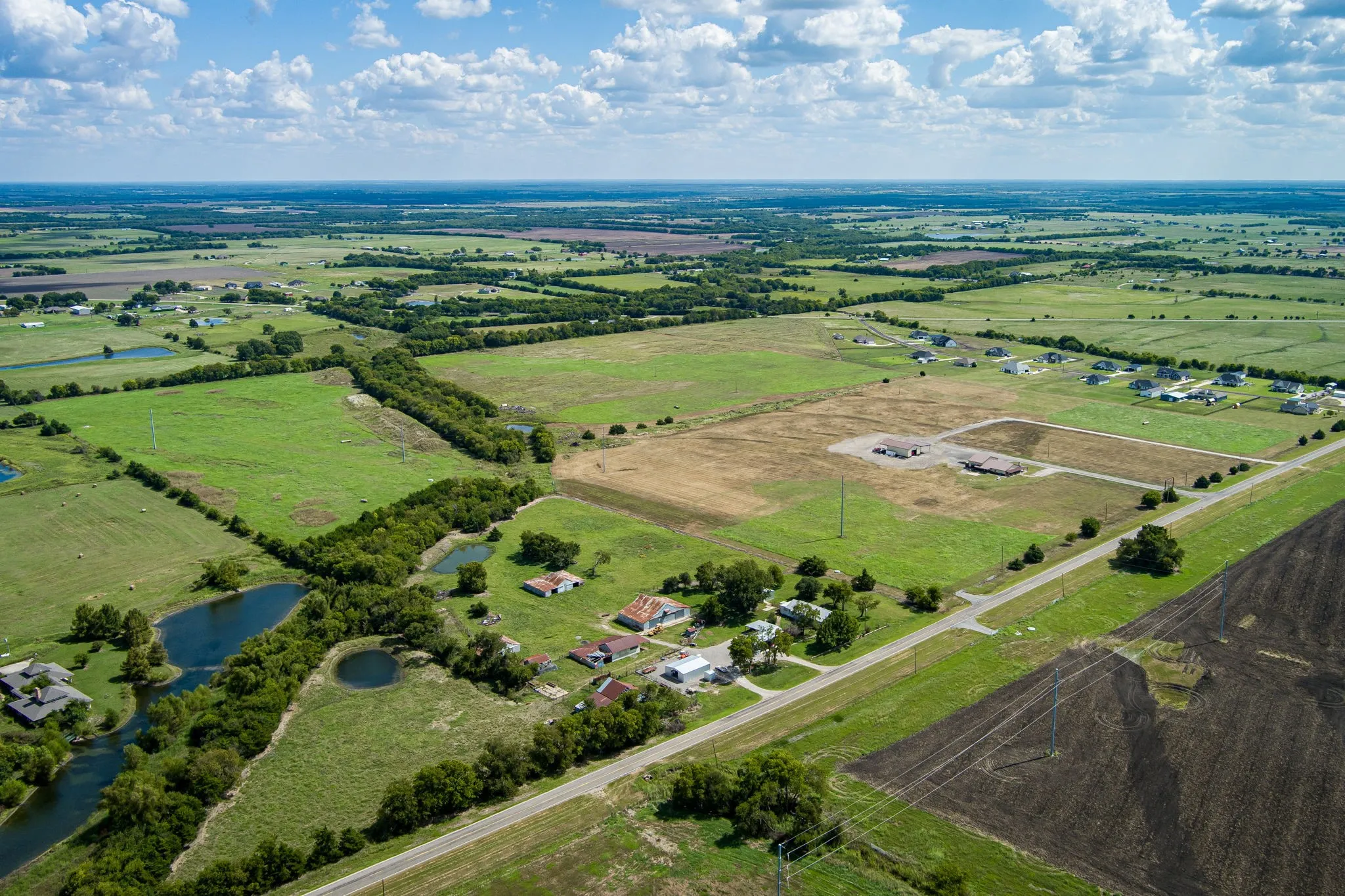 Expansive rural landscape featuring extensive green fields, agricultural areas, and scattered residential properties