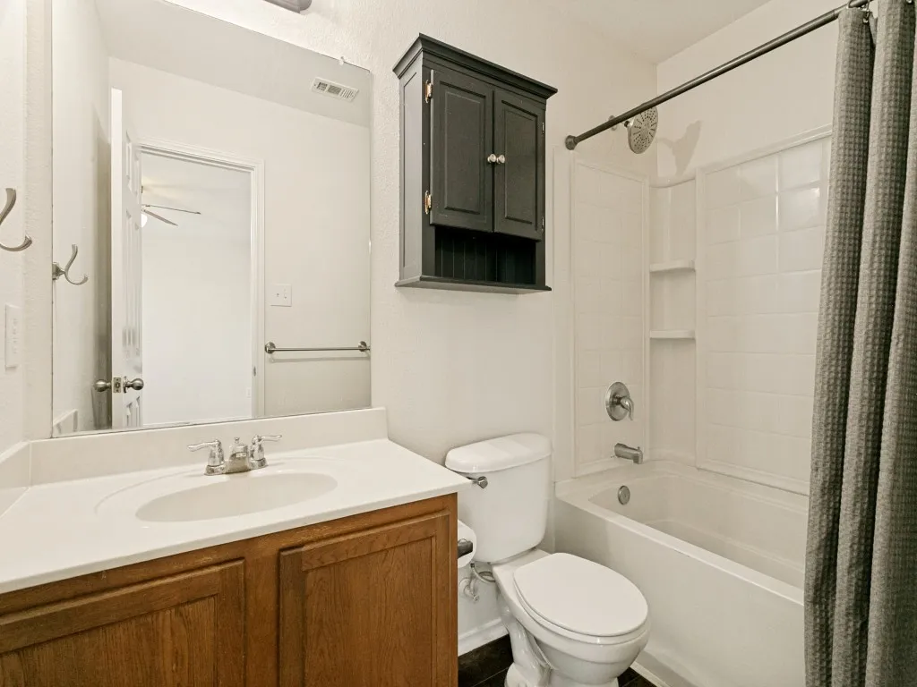 Bathroom featuring a wood-finish vanity with an integrated sink, a white countertop, and a wall-mounted​​‌​​​​‌​​‌‌​‌‌​​​‌‌​‌​‌​‌​​​‌​​ mirror