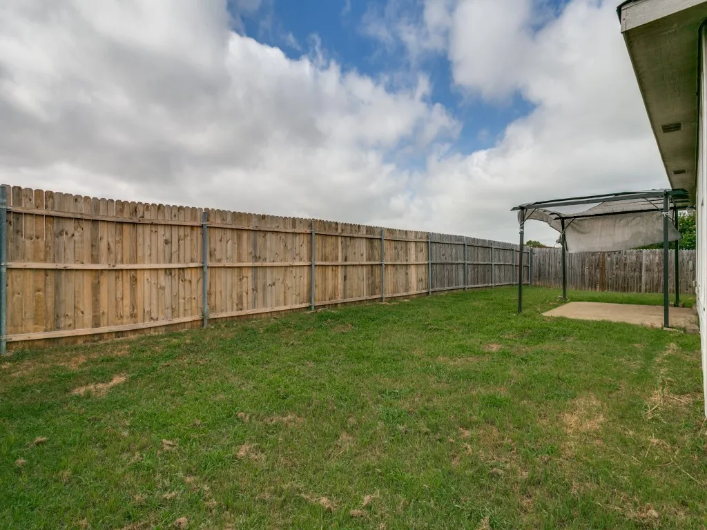 Expansive backyard featuring a full wood privacy fence, a concrete patio, and a metal framed pergola