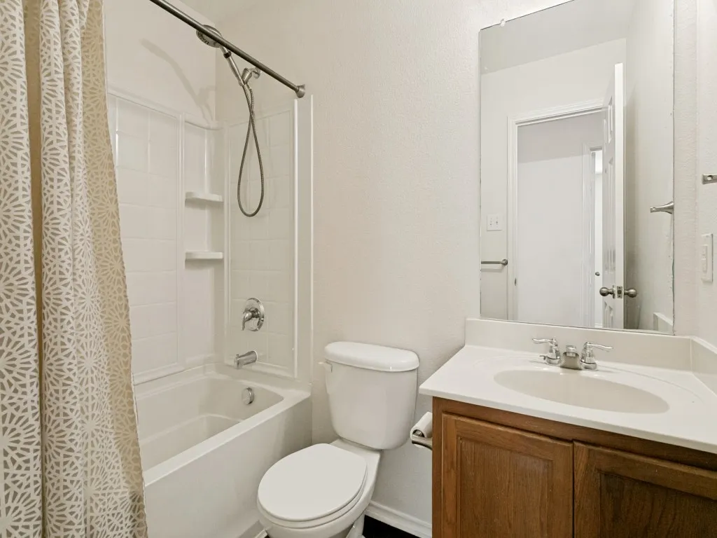 Bathroom featuring a bathtub with an integrated shower, white tiled surround, and chrome fixtures