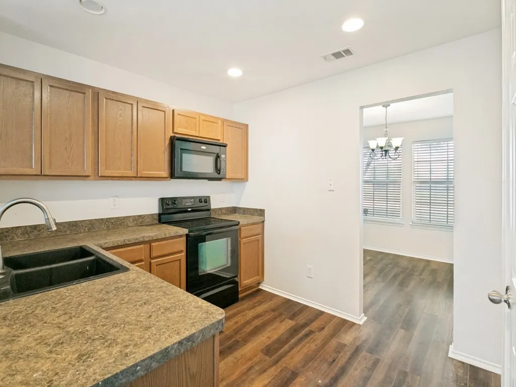 Kitchen featuring wood-finish cabinetry, dark countertops, and stainless steel sink