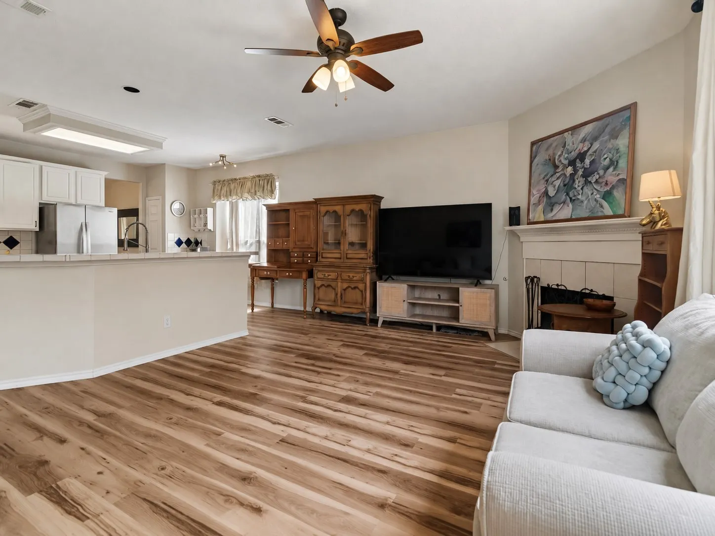 Expansive wood-finish flooring throughout, complemented by a ceiling fan with integrated lighting