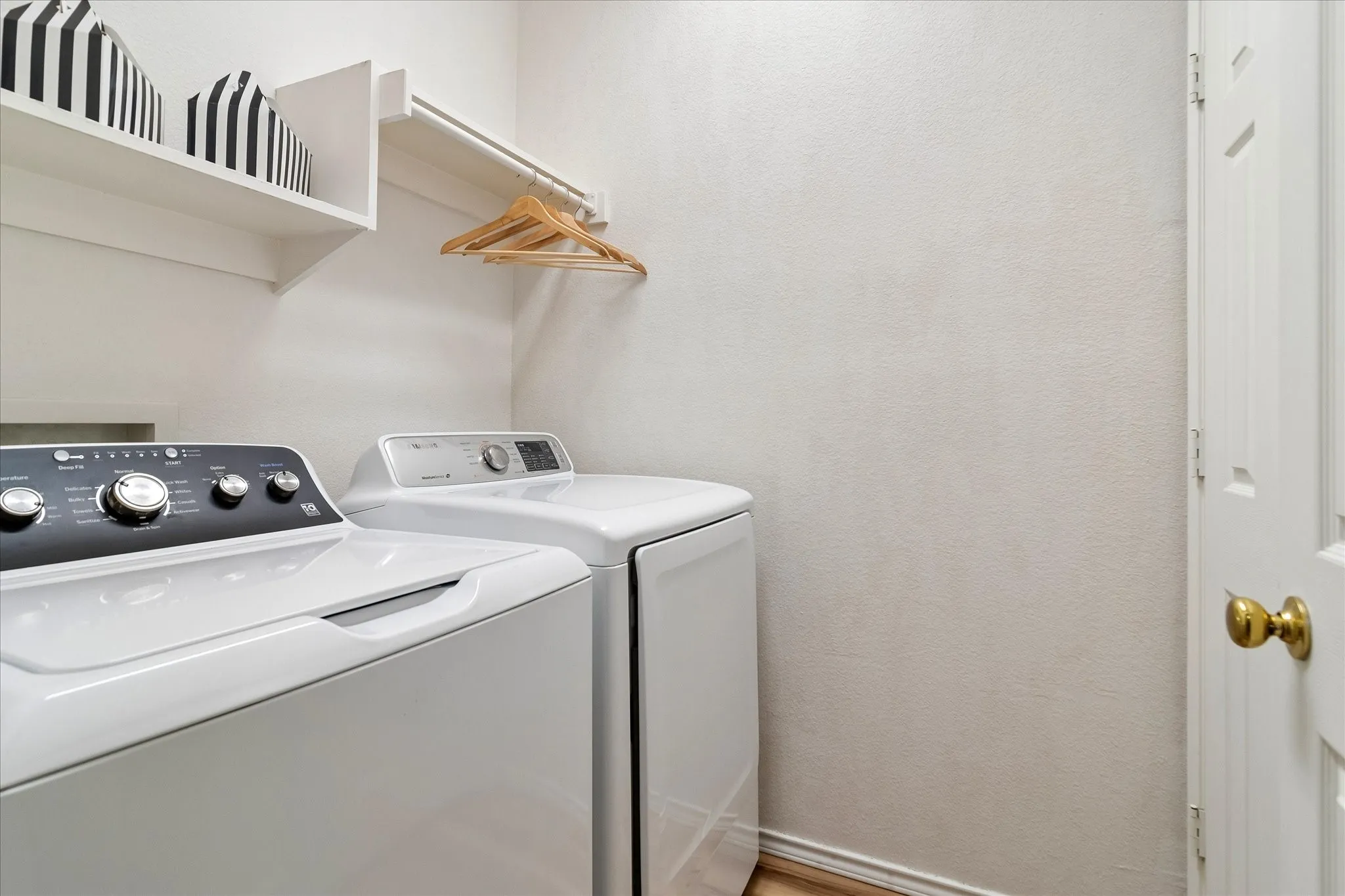 Laundry area featuring a built-in shelving unit, a wall-mounted hanging rod, and wood-finish flooring