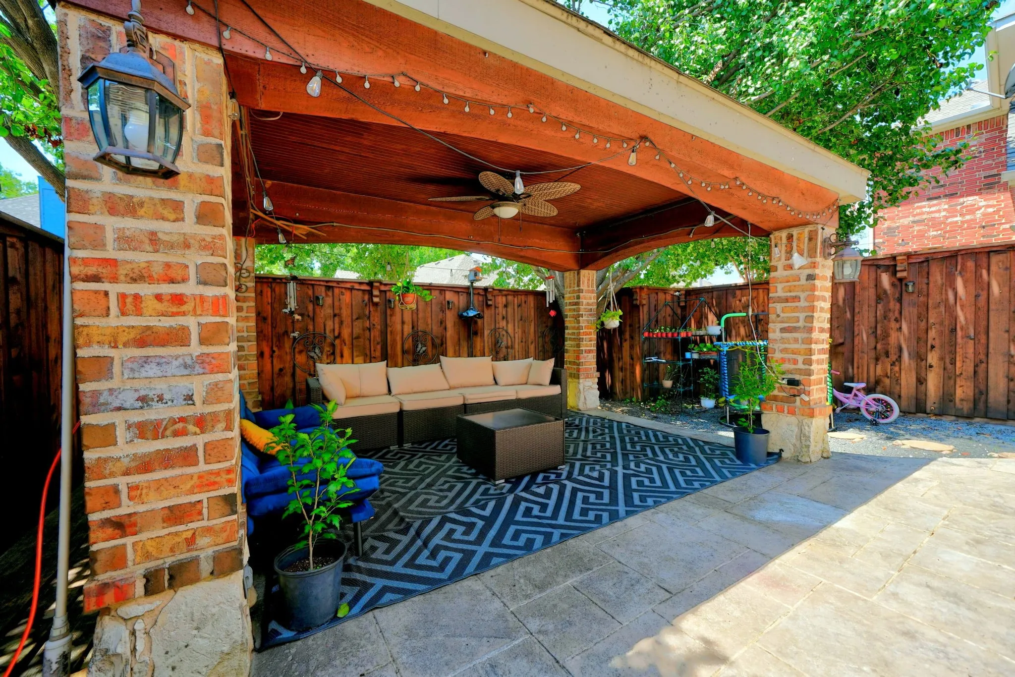 Covered patio featuring brick columns, a wood-paneled ceiling, and a ceiling fan