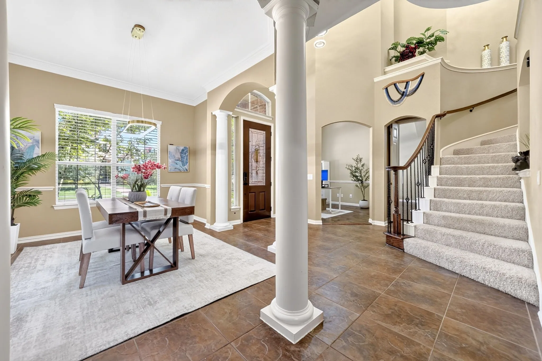 Grand entry featuring a curved staircase with dark wood and iron balusters, high ceilings, and tile flooring