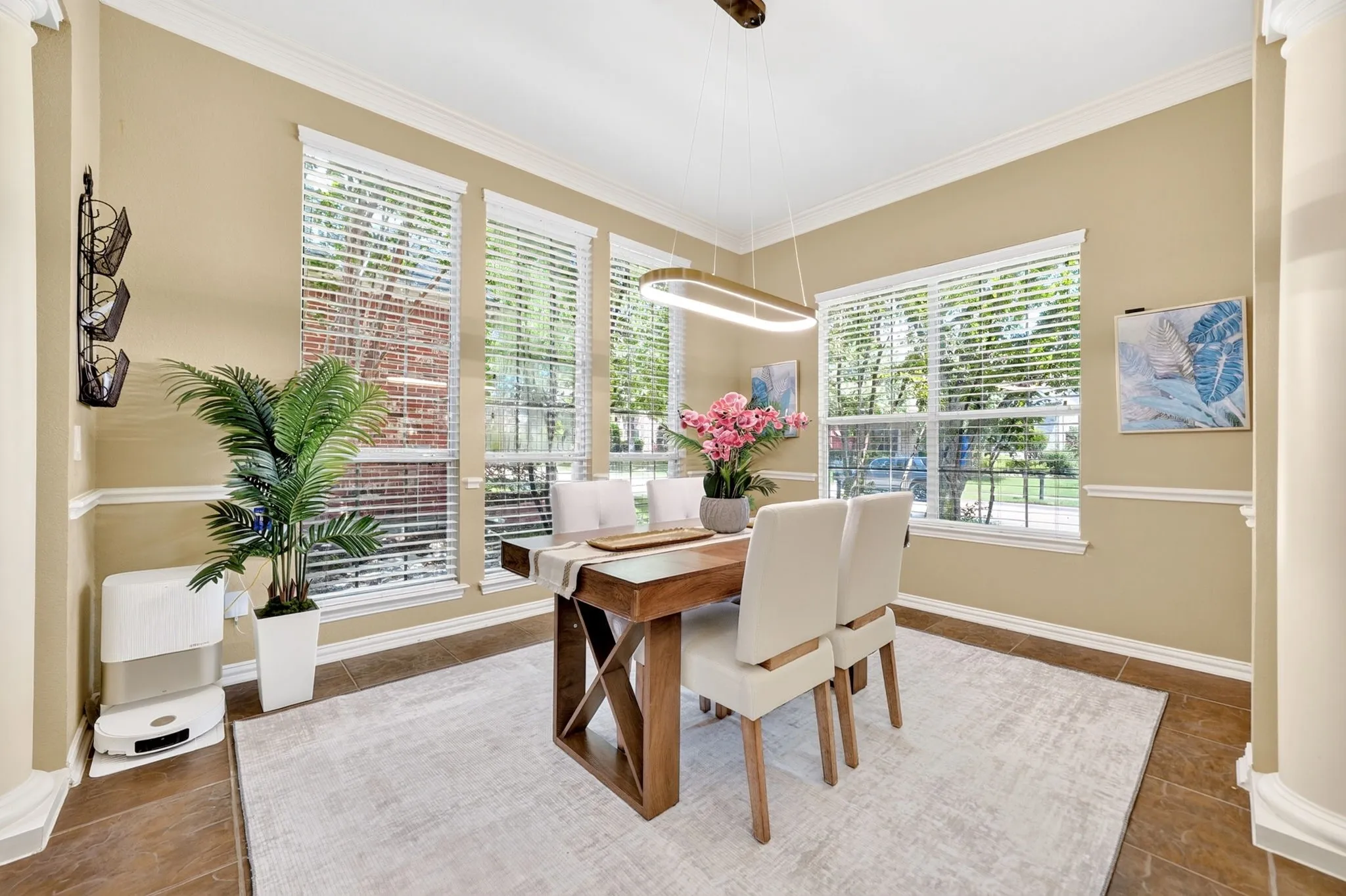 Formal dining area featuring large windows with blinds, crown molding, chair rail molding, tile flooring, and a contemporary linear chandelier