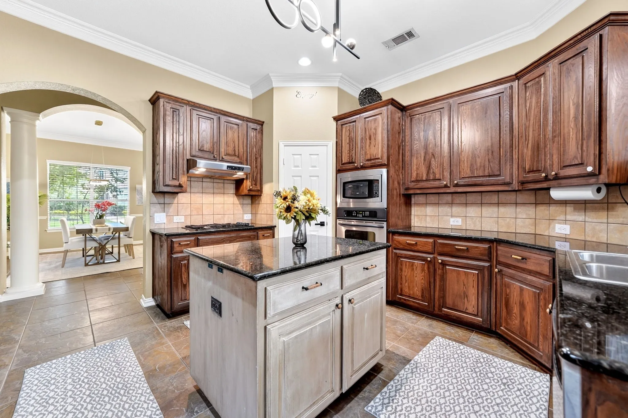 Kitchen featuring dark wood cabinetry, granite countertops, tile flooring, and a central island with a contrasting finish