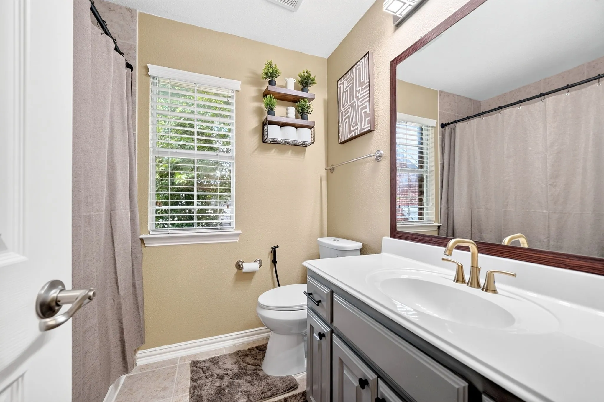 Bathroom vanity featuring an integrated sink, gold-tone faucet, and dark wood-framed mirror