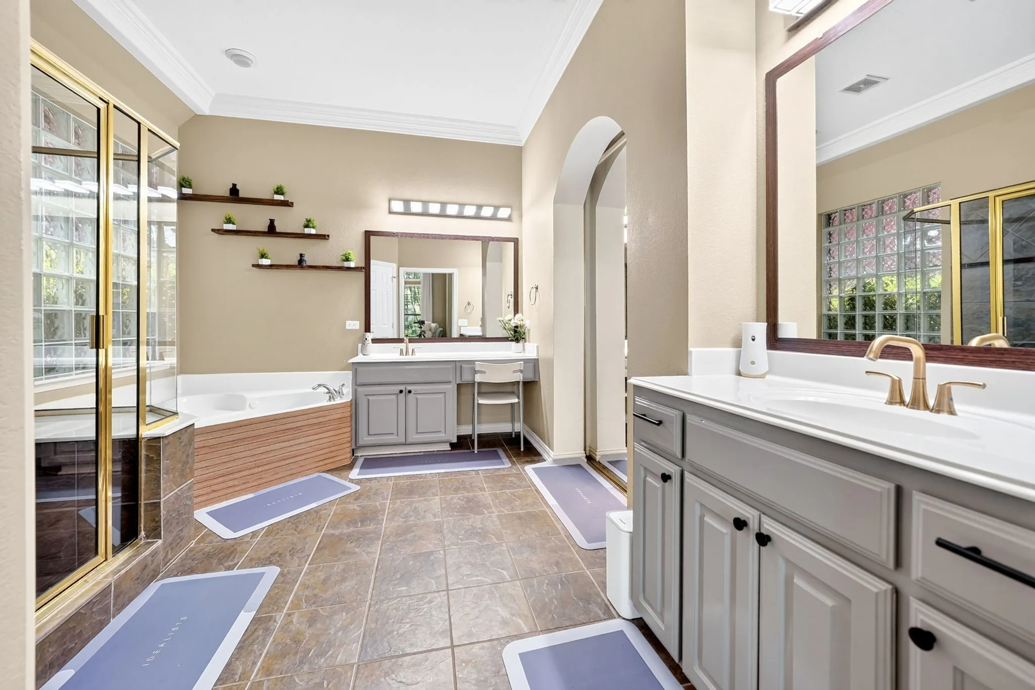 Spacious bathroom featuring a corner soaking tub, separate glass-enclosed shower, dual vanity with ample counter space, and tile flooring