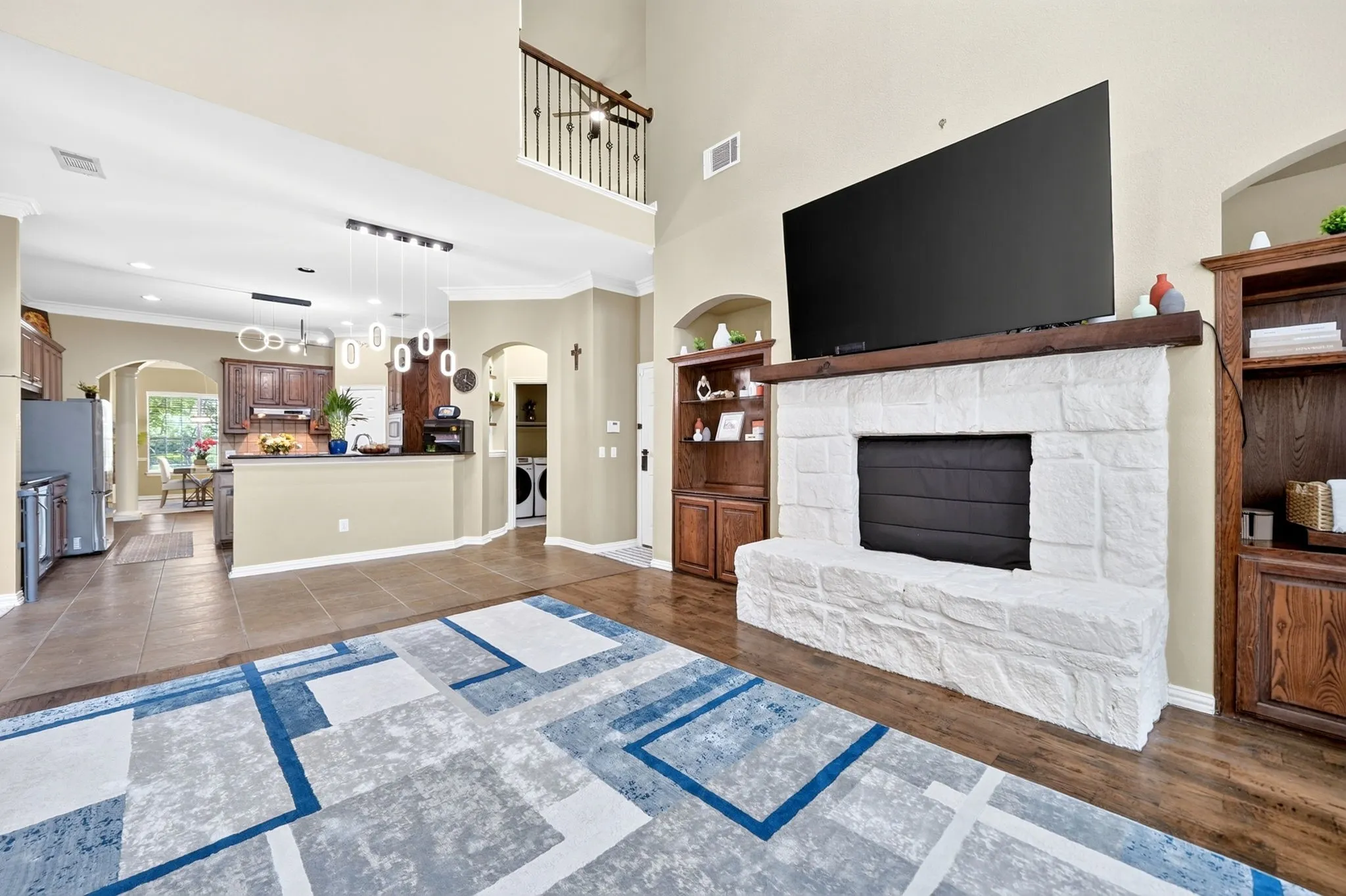 Spacious living area featuring a prominent stone-clad fireplace with a wood mantel, flanked by built-in wood cabinetry