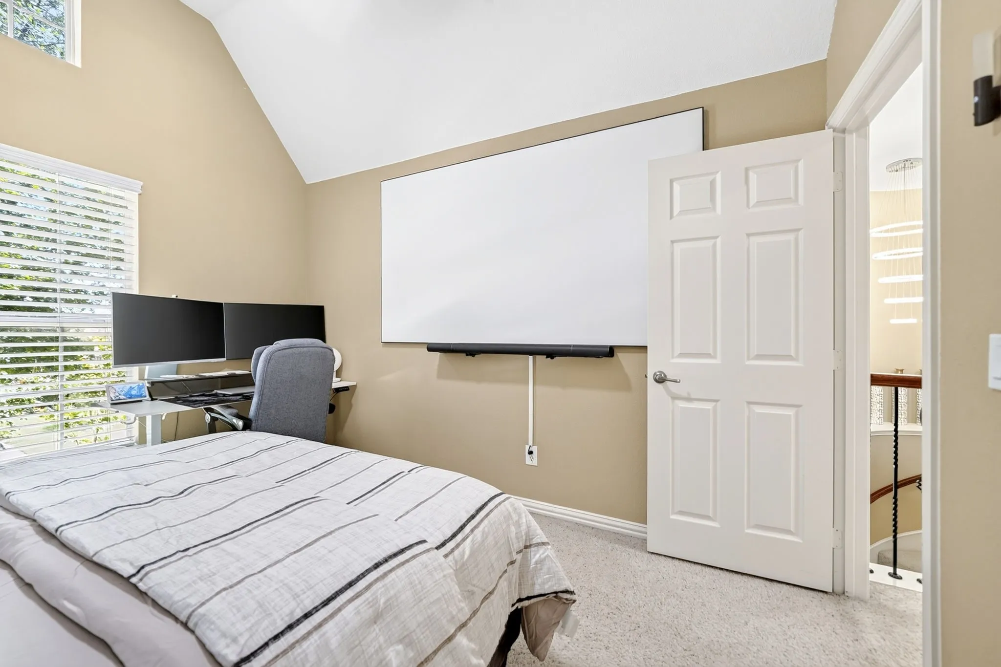 Vaulted ceilings enhance this room featuring light-toned walls and carpet flooring