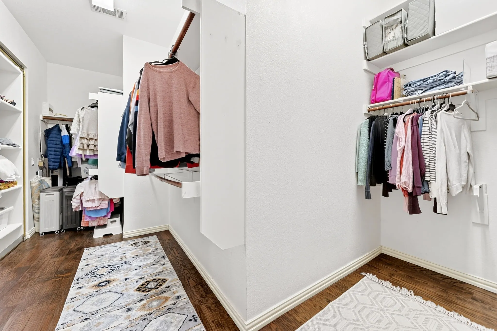 Walk-in closet featuring wood-finish flooring, white baseboards, and built-in shelving units