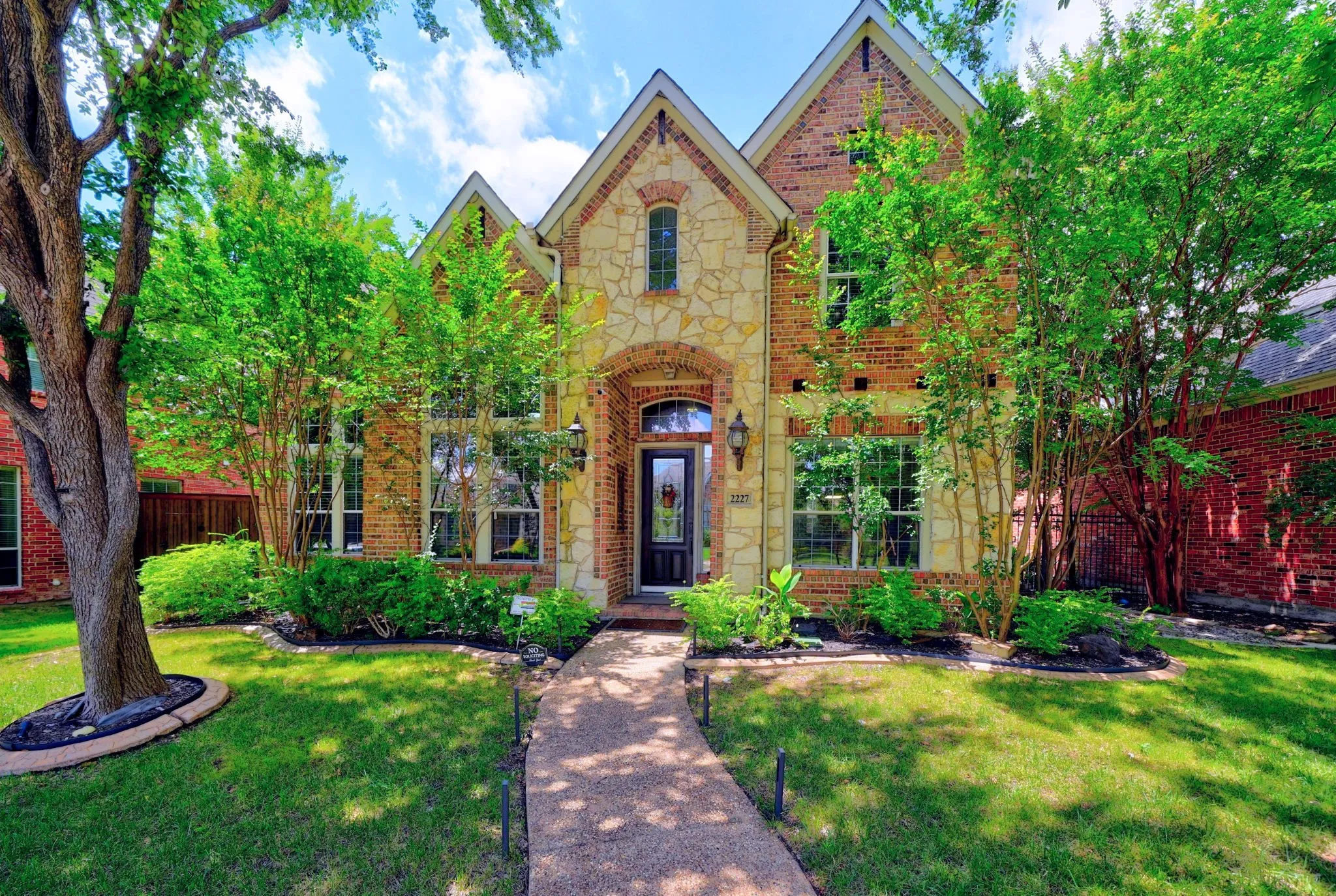 Stately brick and stone facade residence featuring an arched entryway with a dark wood front door