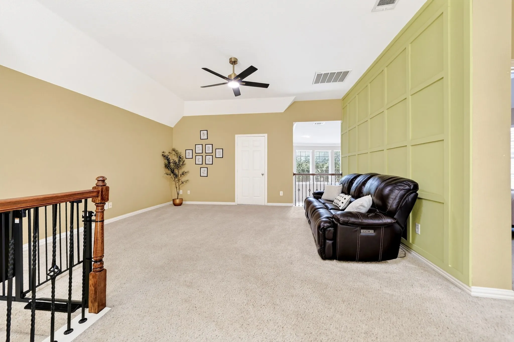Spacious upper-level room featuring light neutral carpeting and a decorative paneled accent wall