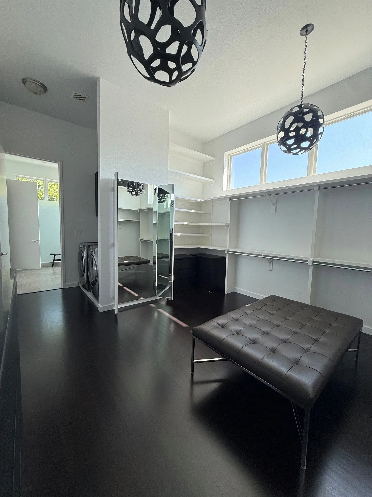 Dark wood-finish flooring with built-in shelving, hanging rods, and high windows