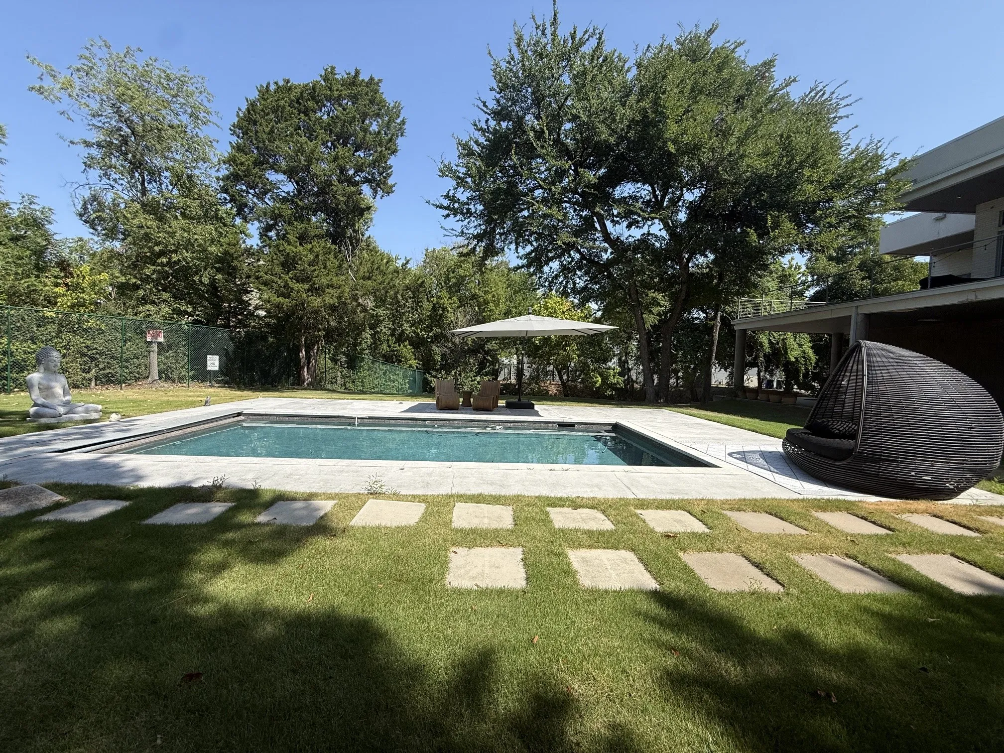 Rectangular swimming pool with a stone coping and surrounding concrete patio