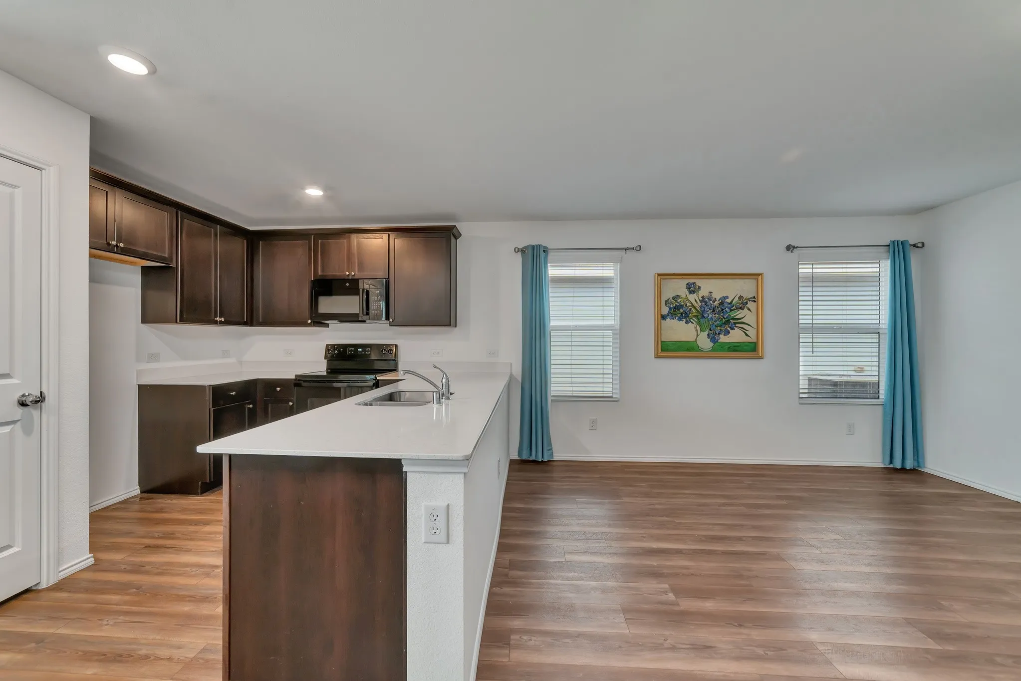 Kitchen featuring dark wood cabinetry, light countertops, and integrated black appliances
