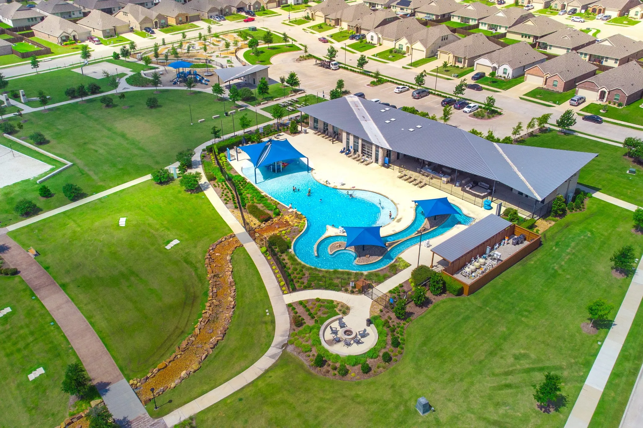 Community amenity center with a large resort-style swimming pool, covered lounge areas, and a structured clubhouse building