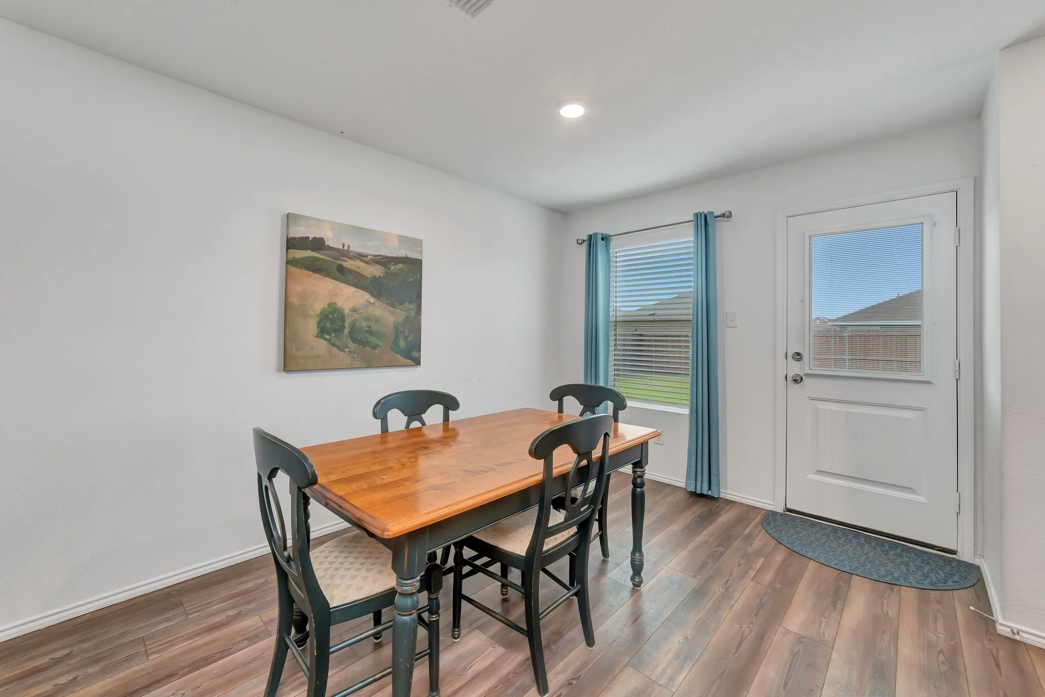 Dining area featuring wood-finish flooring, white walls, a single recessed light fixture, and a window with blinds